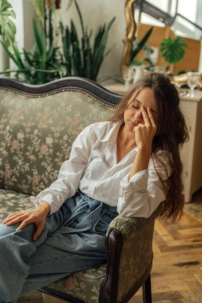 Mastering the First Impression: Your intriguing post title goes here A woman relaxes on a floral vintage sofa in a cozy, light-filled room with plants.